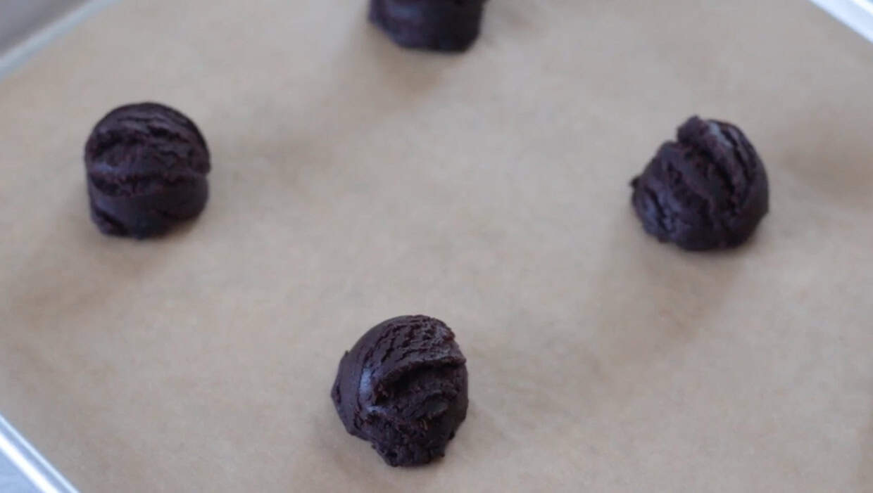 Balls of chocolate cookie dough on baking sheet.