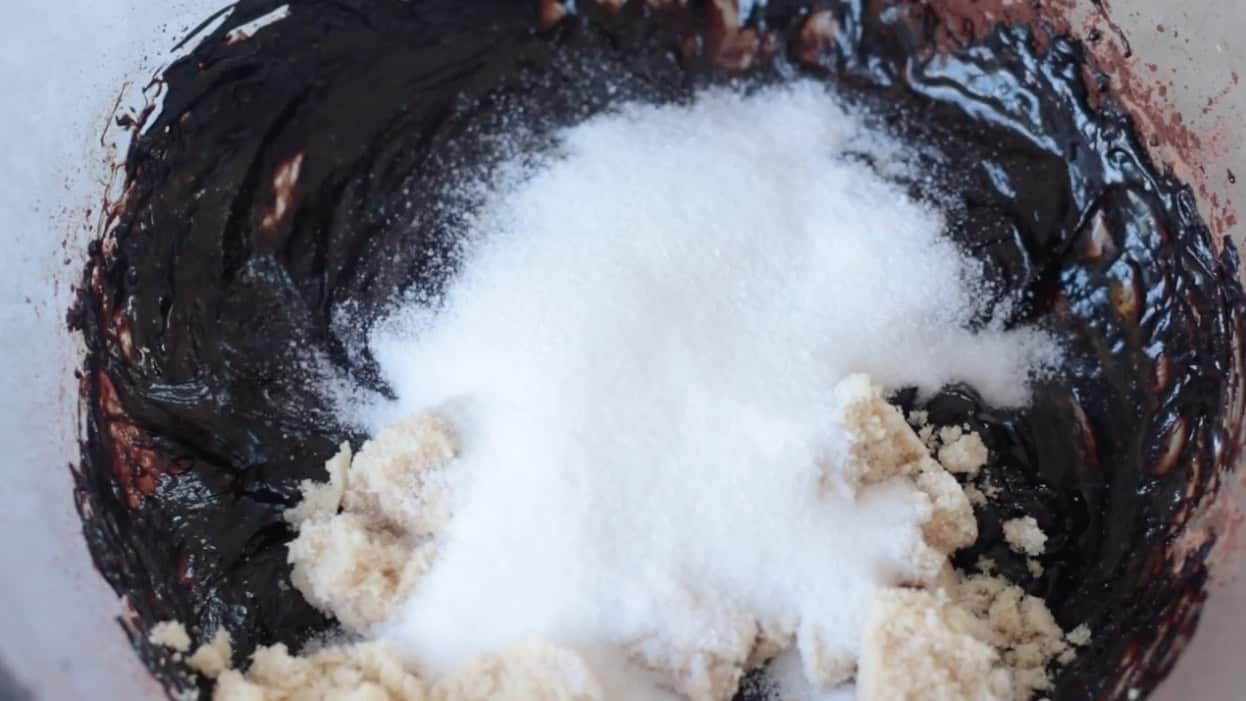 Sugar and brown sugar added to cocoa powder and melted butter.