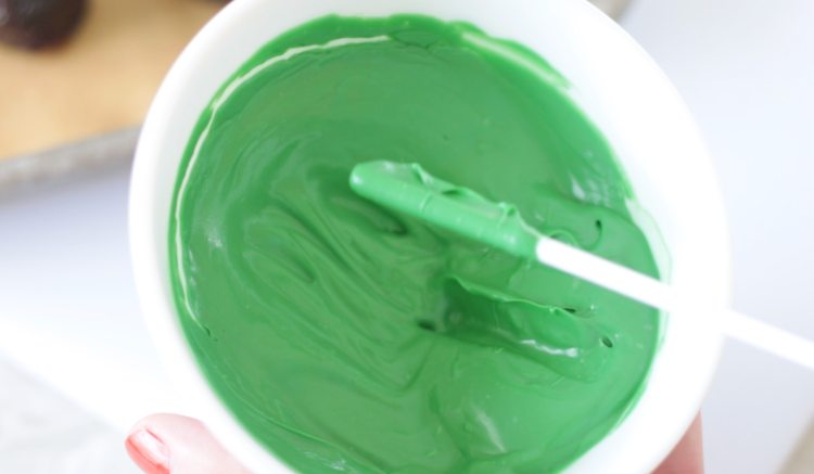 bowl of green melting chocolate with lollipop dipped