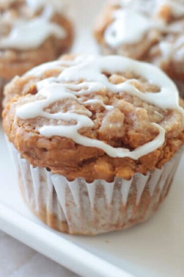 White platter of pumpkin muffins drizzled in icing.