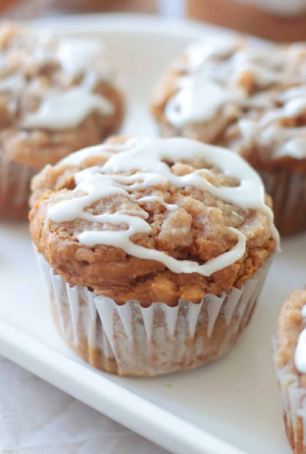 White platter with pumpkin muffins drizzled with vanilla glaze.