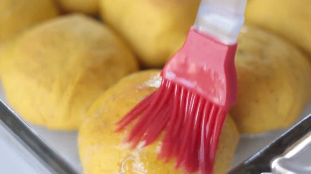Pastry brush brushing rolls with melted butter.