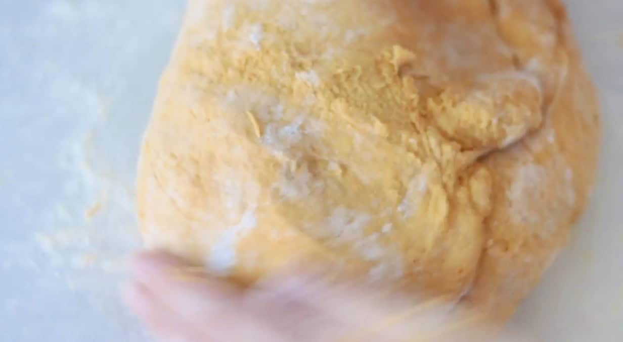 Pumpkin roll dough kneaded on floured surface.