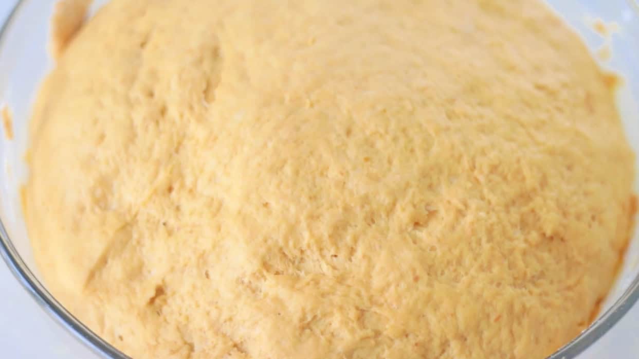 Bowl of pumpkin roll dough rising in bowl.