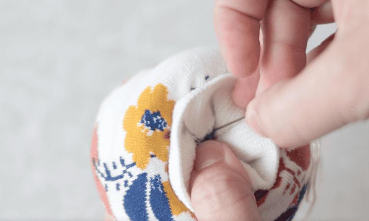 needle and thread going into sock