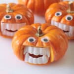 Four mini pumpkins with vampire fangs and craft eyes.