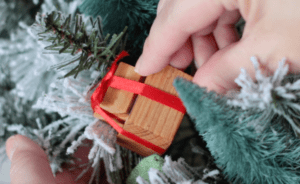 hand placing wooden gift on wreath