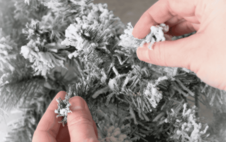 Two hands fluffing wreath base.