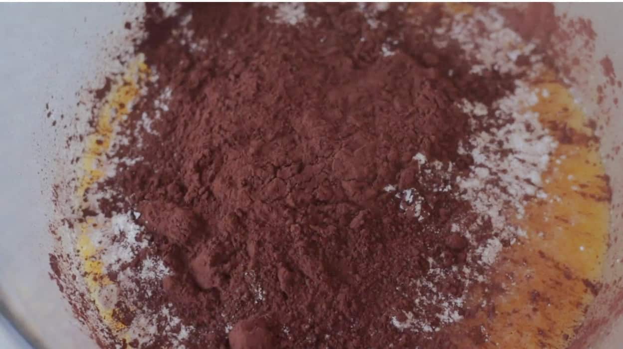 Mixing bowl with flour and baking cocoa poured over butter and sugar mixture.