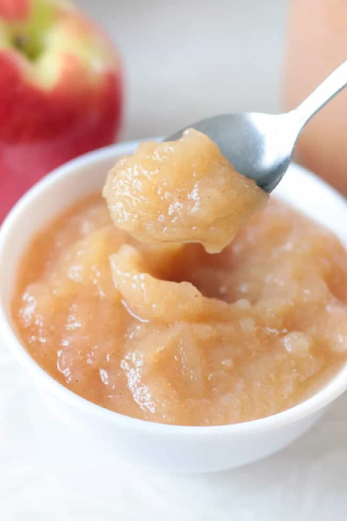 Small white bowl of applesauce and spoon.