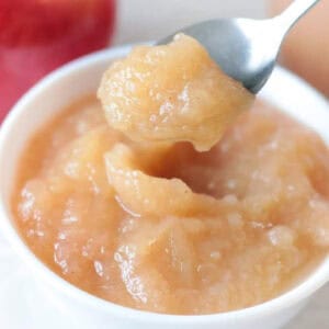 Small white bowl of applesauce with a spoon.