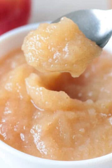 Small white bowl of applesauce with a spoon.