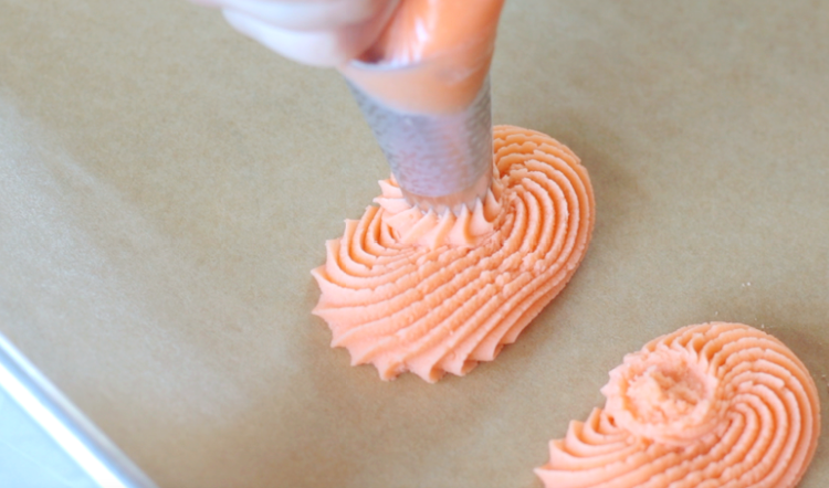 frosting bag piping dough into pumpkin shapes