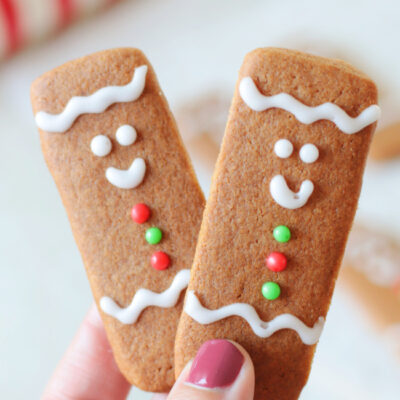 hand holding two gingerbread cookie sticks