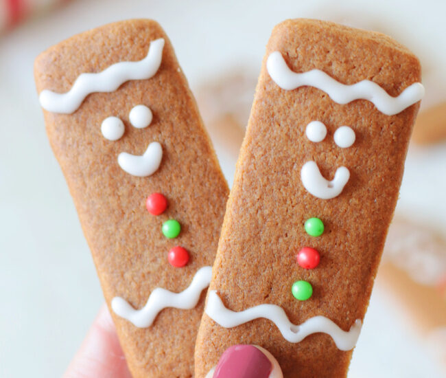 hand holding two gingerbread cookie sticks