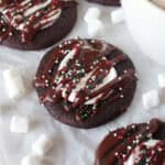 Hot cocoa cookies with sprinkles on table with cup of hot cocoa.