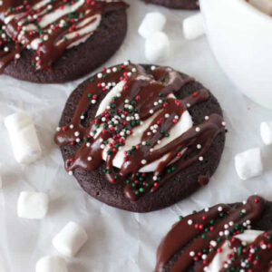 Hot cocoa cookies with sprinkles on table with cup of hot cocoa.