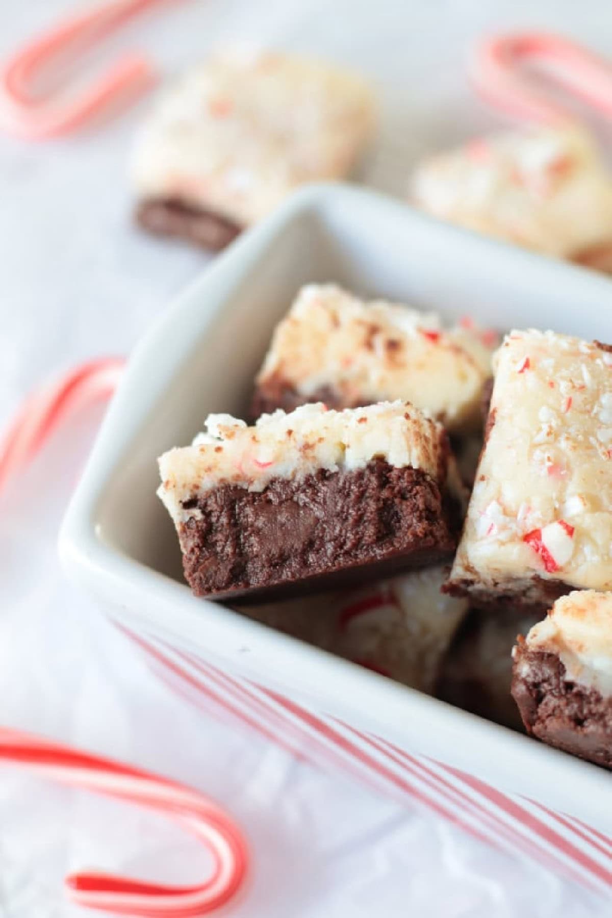 Squares of peppermint fudge in white and red striped dish.