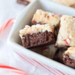 Squares of peppermint fudge in white and red striped dish.