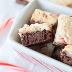 Squares of peppermint fudge in white and red striped dish.