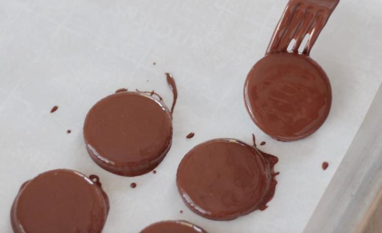 fork sliding chocolate covered oreo onto parchment paper