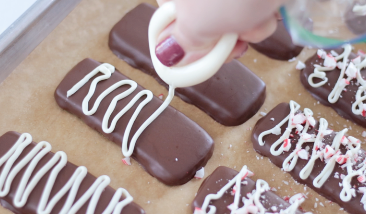 white chocolate being drizzled over chocolate dipped cookies