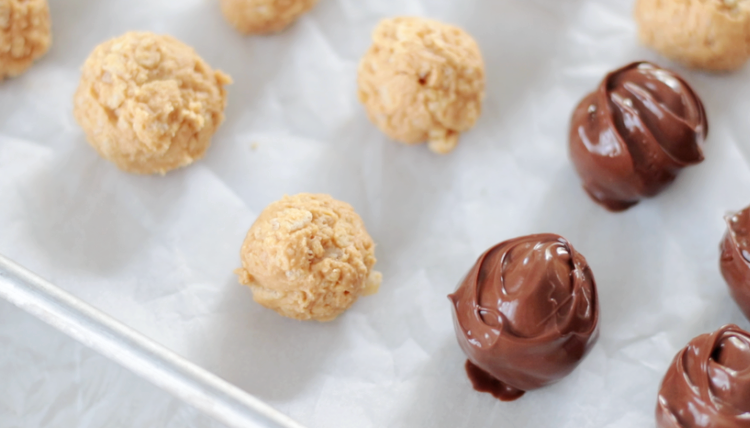 peanut butter balls on baking sheet, some dipped in chocolate