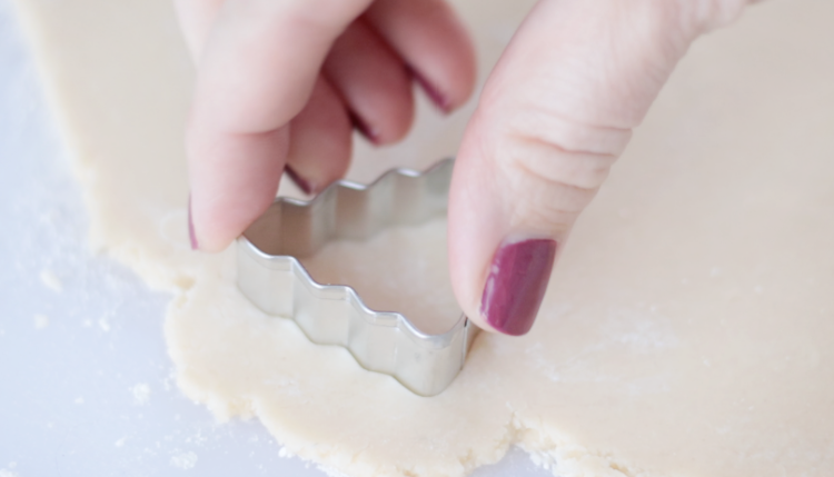 hand pressing tree cookie cutter into cookie dough