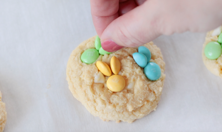 hand placing M&M candies onto cookie in a bunny shape