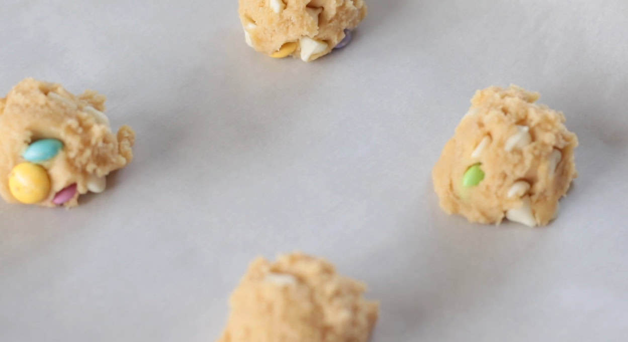 Baking sheet with scoops of M&M cookie dough.