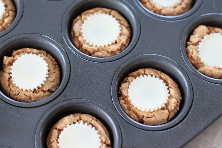 peanut butter cups pressed into peanut butter cookie cups in pan