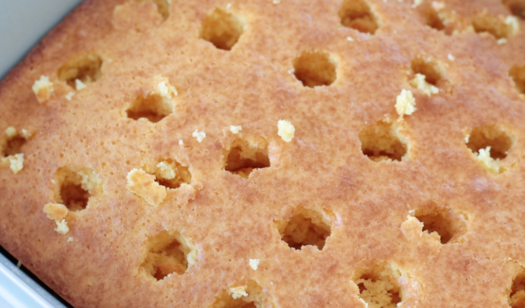 baked yellow cake with holes poked through.