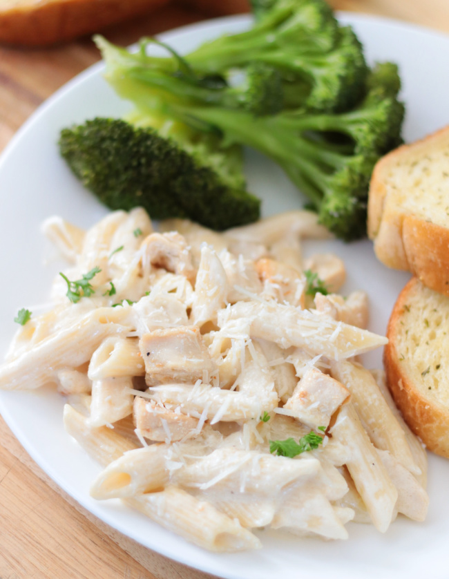 penne Alfredo on plate with bread and broccoli