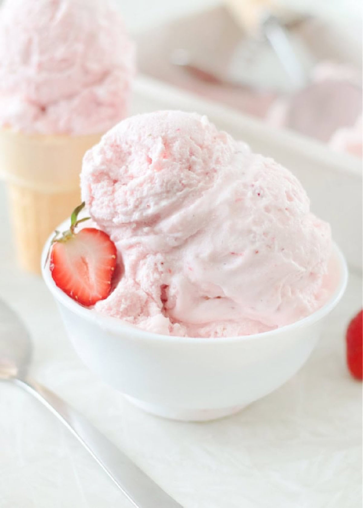 Small white bowl with two scoops of strawberry ice cream.