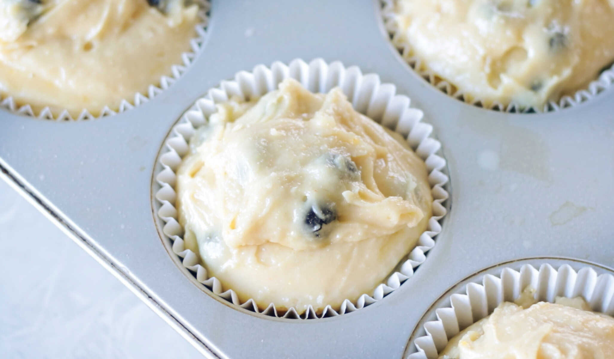 Muffin pan of unbaked blueberry muffin batter.