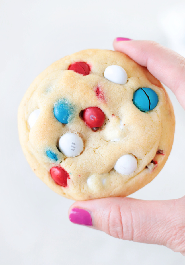 hand holding a red, white and blue M&M cookie