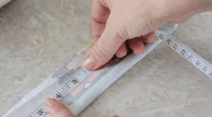 hand holding a measuring tape against fabric