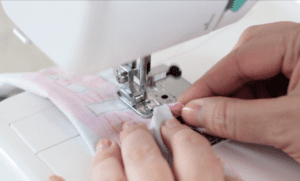 hands holding fabric as it is sewn on sewing machine