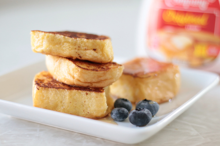 Hawaiian roll French toast stacked on a plate with blueberries