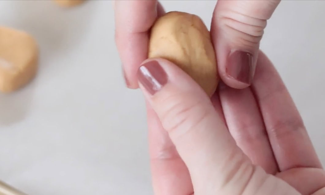 Hands forming ball of peanut butter into ghost shape.