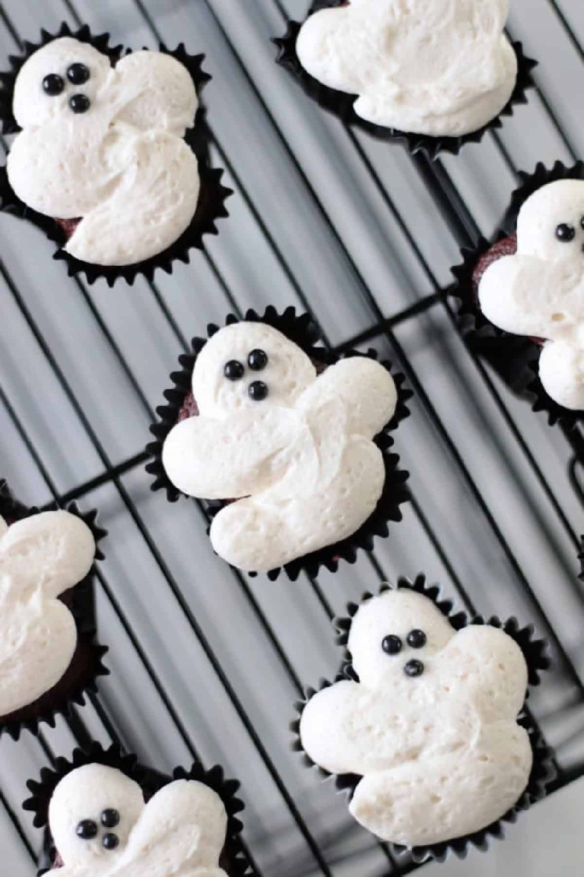 Ghost cupcakes on a wire cooling rack.