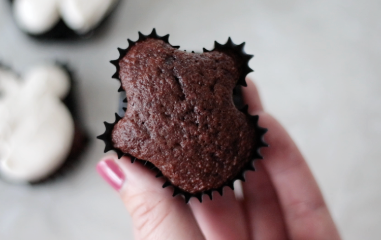 hand holding unfrosted chocolate cupcake shaped like a ghost
