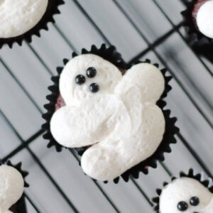 Frosted ghost cupcake on wire cooling rack.