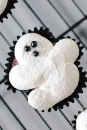 Frosted ghost cupcake on wire cooling rack.