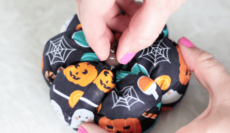 hand gluing felt stem on top of pumpkin