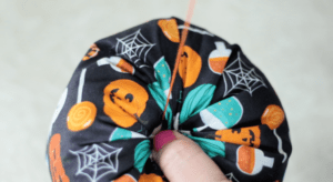 thread being pulled through stuffed pumpkin.