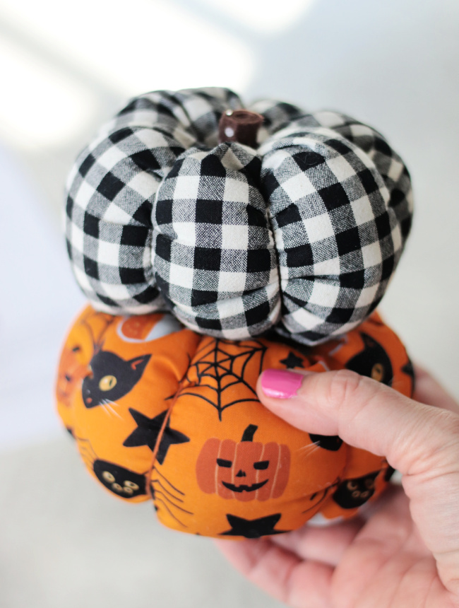 hand holding two fabric pumpkins