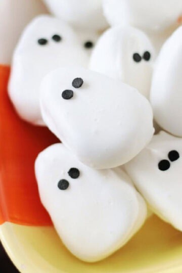 Candy corn bowl of peanut butter ghosts covered in white chocolate.
