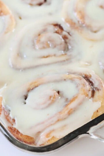 Baking dish of baked cinnamon rolls and icing.