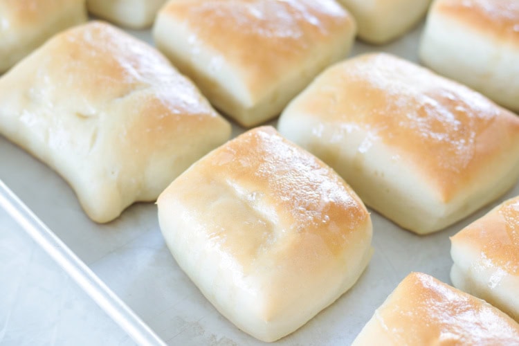 baked rolls brushed with butter on baking sheet